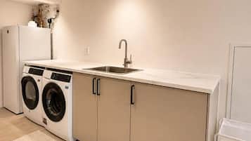 Cocina compacta con un lavamanos, dos lavadoras y un refrigerador.