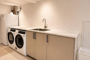 Cocina compacta con un lavamanos, dos lavadoras y un refrigerador.