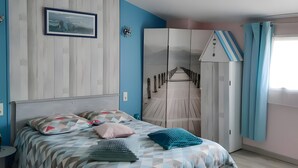Une chambre à coucher comprenant un lit, deux tabourets, une commode et un tableau accroché au mur.