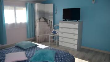 Un dormitori amb un llit, una petita taula de nit, una televisió i un armari.