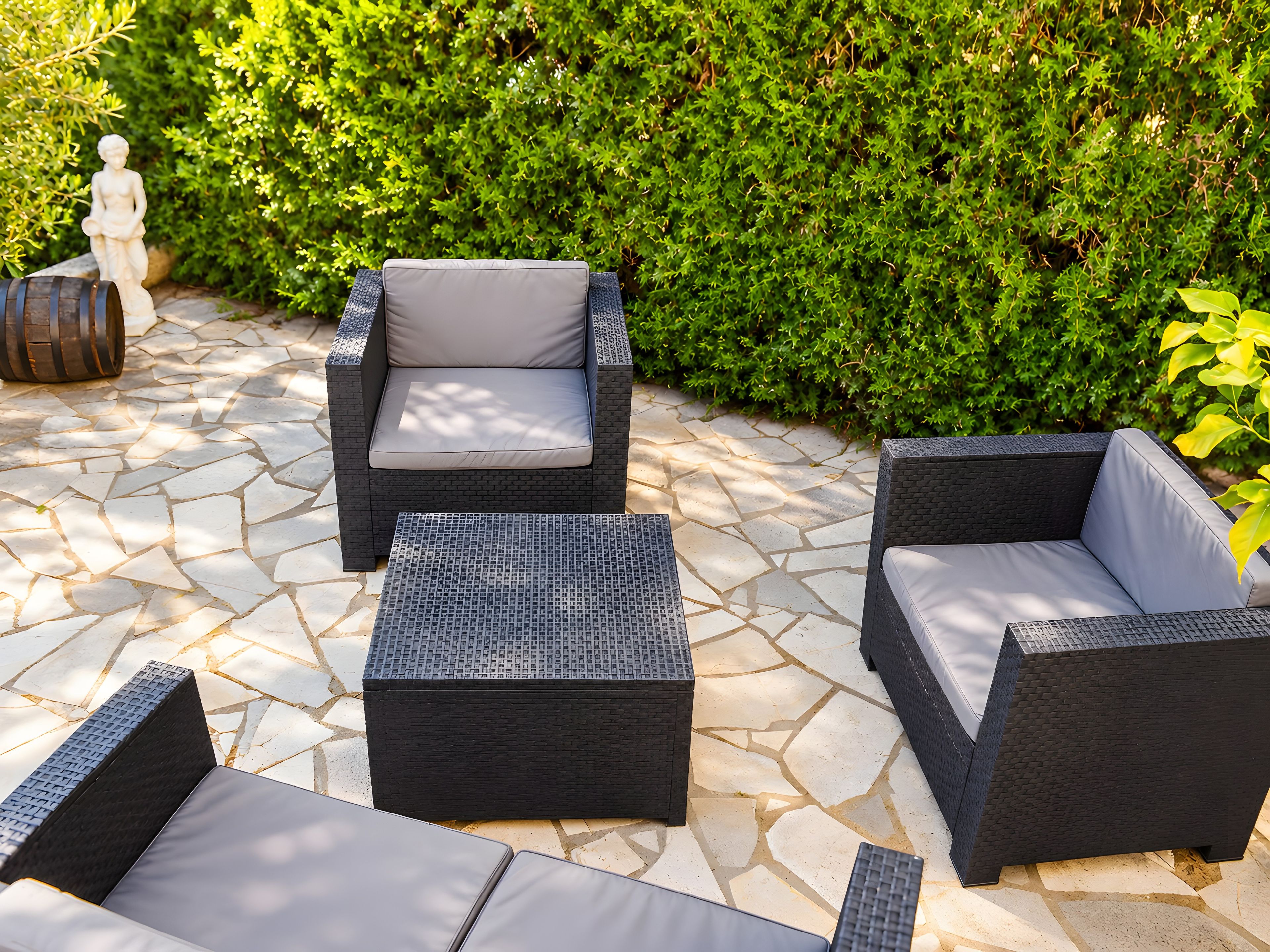 An outdoor seating area with wicker furniture and a stone-tiled floor.