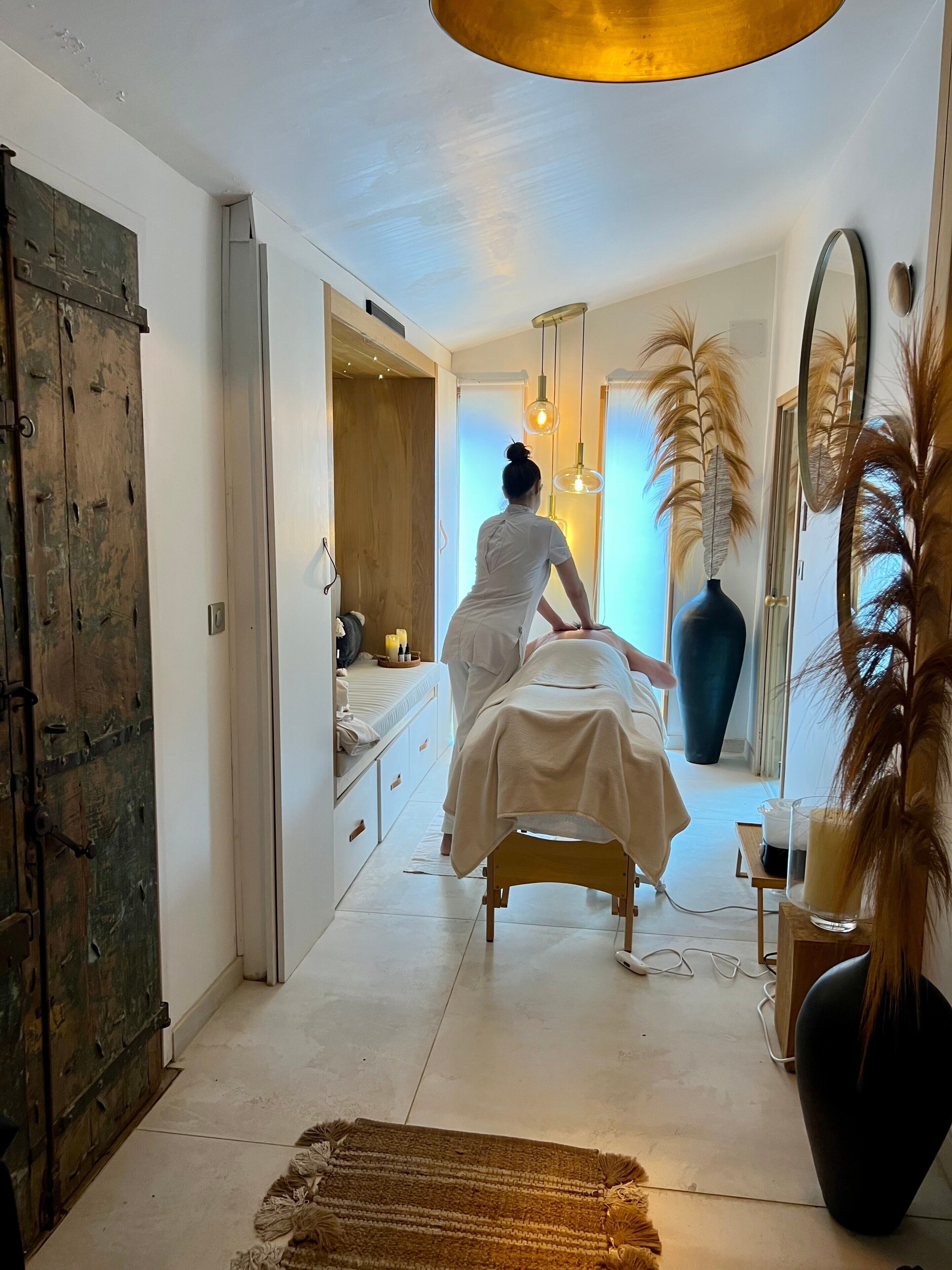 Une pièce comprenant un lit, une armoire en bois, un miroir et un grand vase.
