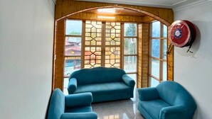A room with a wooden ceiling, a large window with a view, and two blue chairs. - Behtereen Resort (Srinagar)