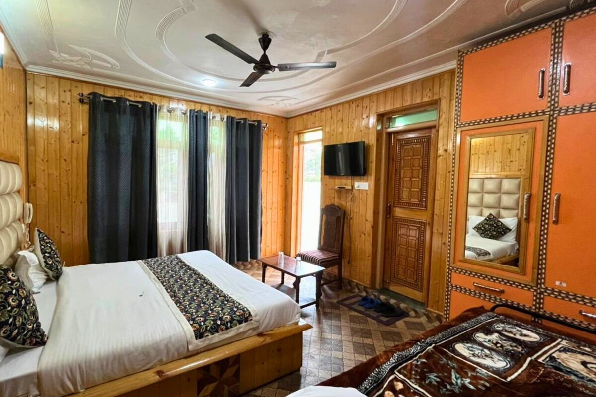 Un dormitorio con cama, una silla, una mesa, un ventilador de techo y un espejo.