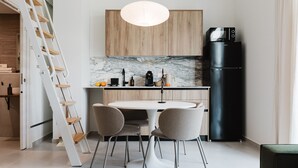 Uma cozinha moderna com uma mesa de jantar redonda, duas cadeiras, uma geladeira e uma escada de madeira.