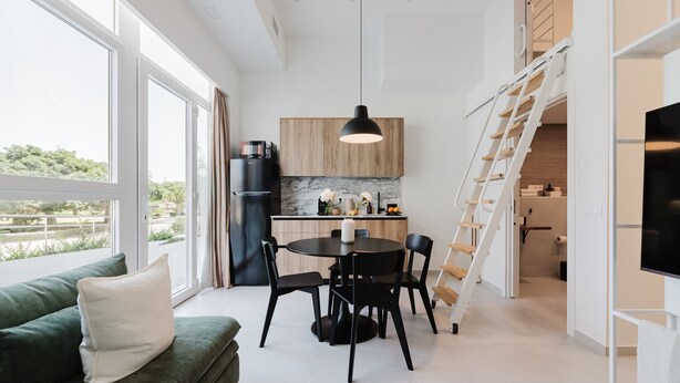 A modern kitchen with a wooden countertop, a black refrigerator, and a dining area with a round table and chairs. - Comfort and Design Facing the Turia Gardens in Valencia (Valencia)