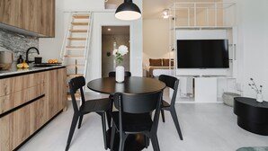 A modern kitchen with a dining area, a staircase, and a TV. - Comfort and Design Facing the Turia Gardens in Valencia (Valencia)