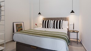 A neatly arranged bedroom with a bed, two pendant lights, a bedside table, and a framed picture on the wall. - Comfort and Design Facing the Turia Gardens in Valencia (Valencia)