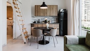 A modern kitchen with a dining area, a black refrigerator, and a wooden cabinet. - Comfort and Design Facing the Turia Gardens in Valencia (Valencia)