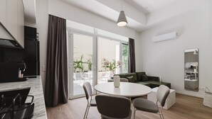 Een moderne keuken met een eethoek, grote ramen en een groene bank.