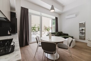 A modern kitchen with a dining area, large windows, and a green sofa. - Comfort Design and a Terrace Facing the Turia Gardens in Valencia (Valencia)