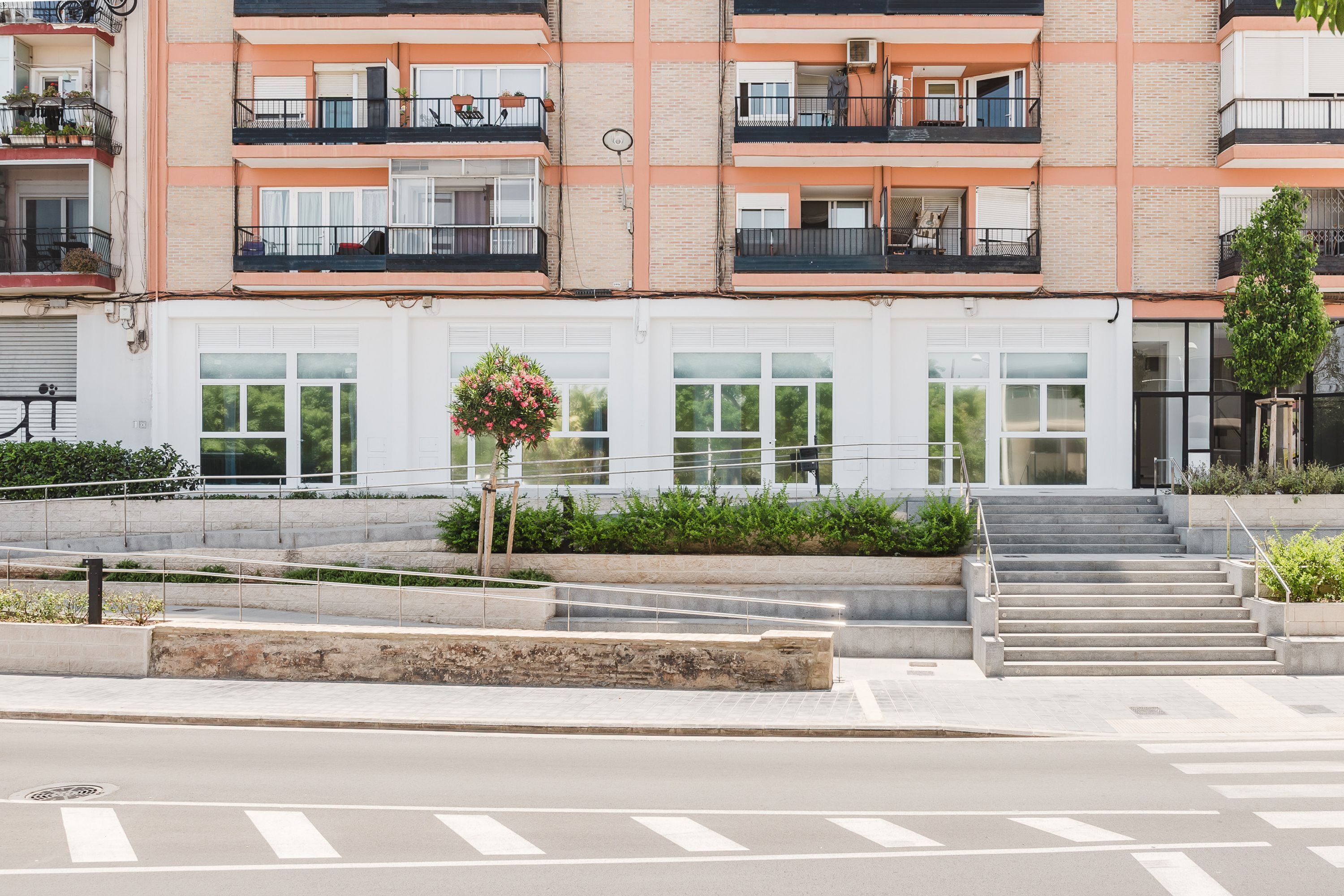 A multi-story residential building with balconies, a staircase, and a small garden area.