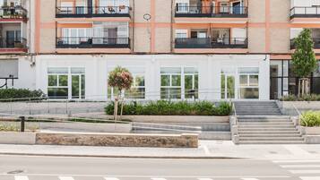 A multi-story residential building with balconies, a staircase, and a small garden area.
