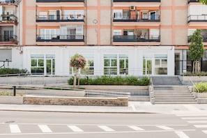 A multi-story residential building with balconies, a staircase, and a small garden area. - Comfort Design and a Terrace Facing the Turia Gardens in Valencia (Valencia)