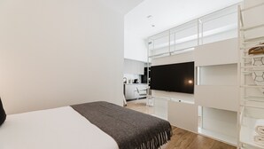 Een moderne hotelkamer met een bed, een televisie, een kitchenette en een inloopkast.