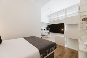 A modern hotel room with a bed, a TV, a kitchenette, and a walk-in closet. - Comfort Design and a Terrace Facing the Turia Gardens in Valencia (Valencia)