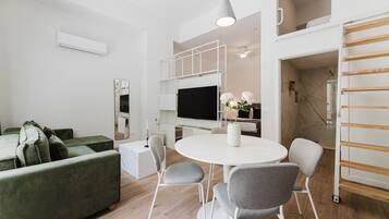 A modern living room with a green sofa, white round table, and grey chairs.