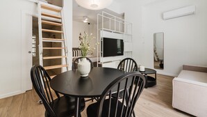 Uma sala de estar moderna com uma mesa de jantar, cadeiras, uma TV e um sofá.