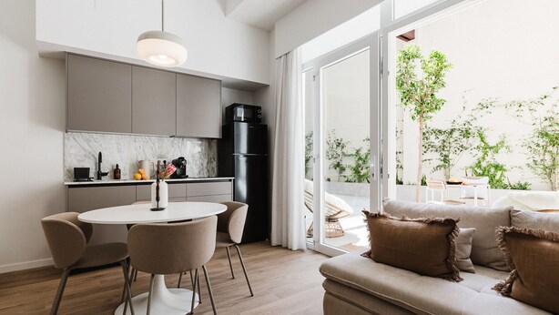 A modern kitchen with a dining area, a sofa, and a view of the outdoors. - Comfort Design and a Terrace Facing the Turia Gardens in Valencia (Valencia)