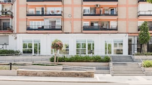 A multi-story residential building with balconies, a staircase, and a small garden area. - Comfort Design and a Terrace Facing the Turia Gardens in Valencia (Valencia)