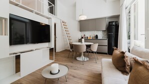A modern kitchen with a dining area, a TV, and a staircase. - Comfort Design and a Terrace Facing the Turia Gardens in Valencia (Valencia)