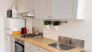Een moderne keuken met witte kastjes, een houten aanrecht, een roestvrijstalen spoelbak en een vaatwasser.