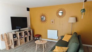 Een woonkamer met een televisie, bank en houten planken.