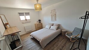 Een slaapkamer met een bed, nachtkastje, lamp, stoel en een hanglamp.
