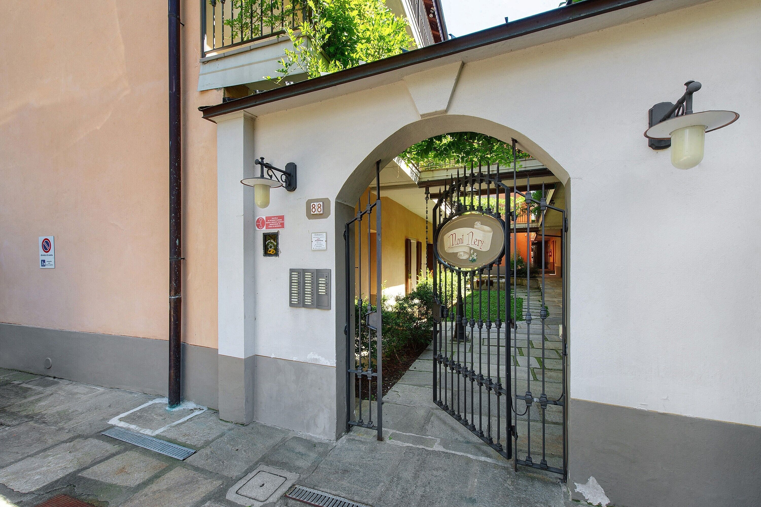 A building entrance with a metal gate, a sign with the number 88, and a wall-mounted light fixture.