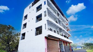 A multi-story building with a flat facade, large windows, and a red door. - Deluxe Collection O Mahabalipuram (Tirukalukundram)