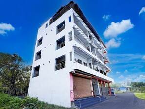 Ein mehrstöckiges Gebäude mit schlichter Fassade, großen Fenstern und einer roten Tür.