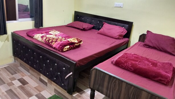 A room with two beds, a window with curtains, a wooden floor, and a wall socket. - Hotel Himalayan View  (Ukhimath)