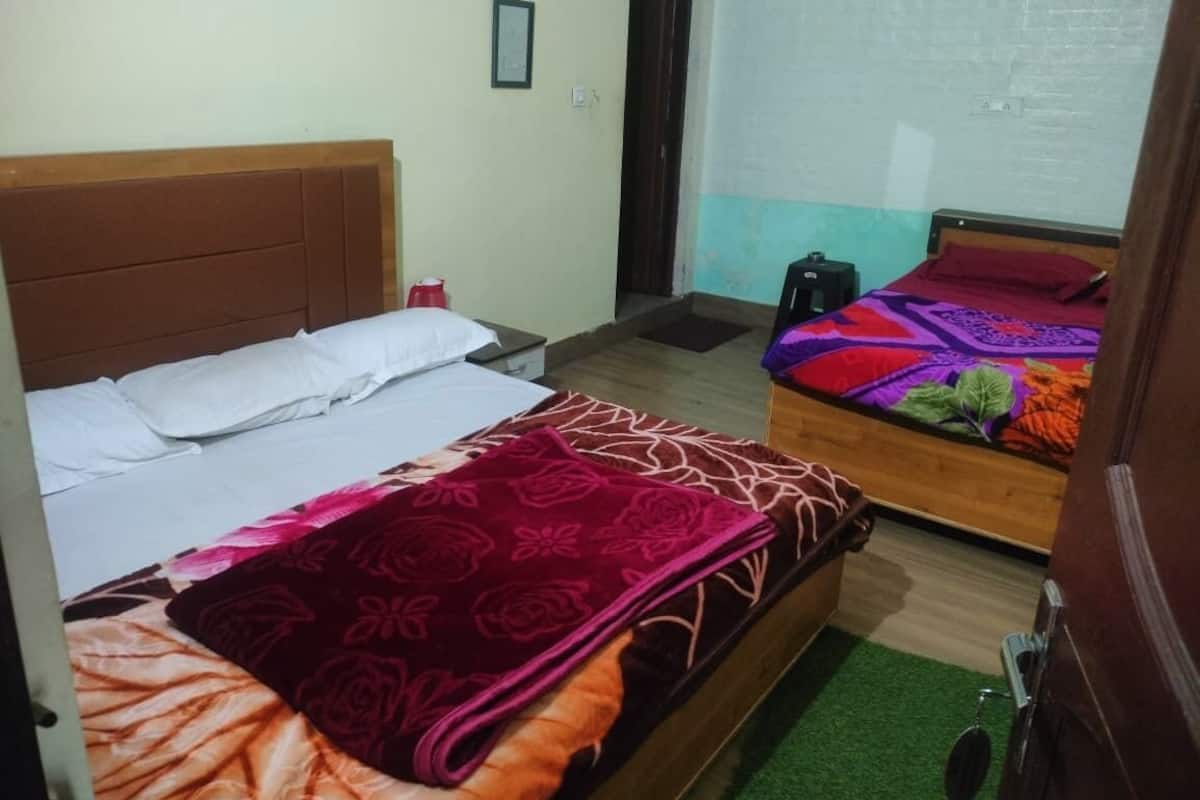 A room with two beds, a wooden headboard, a small table, a chair, and a door.