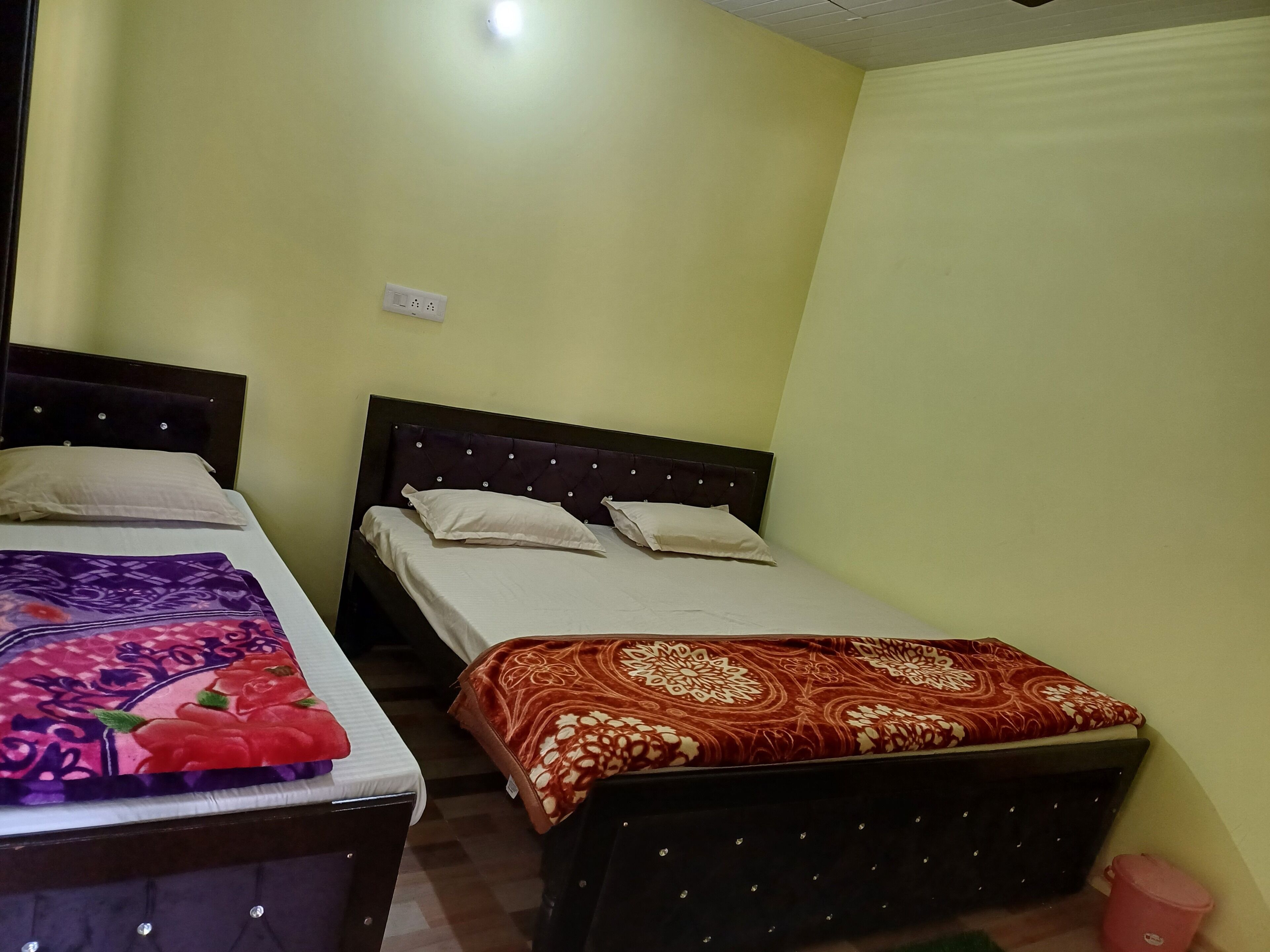 Quarto com duas camas de solteiro, cada uma com uma colcha de padrão diferente.