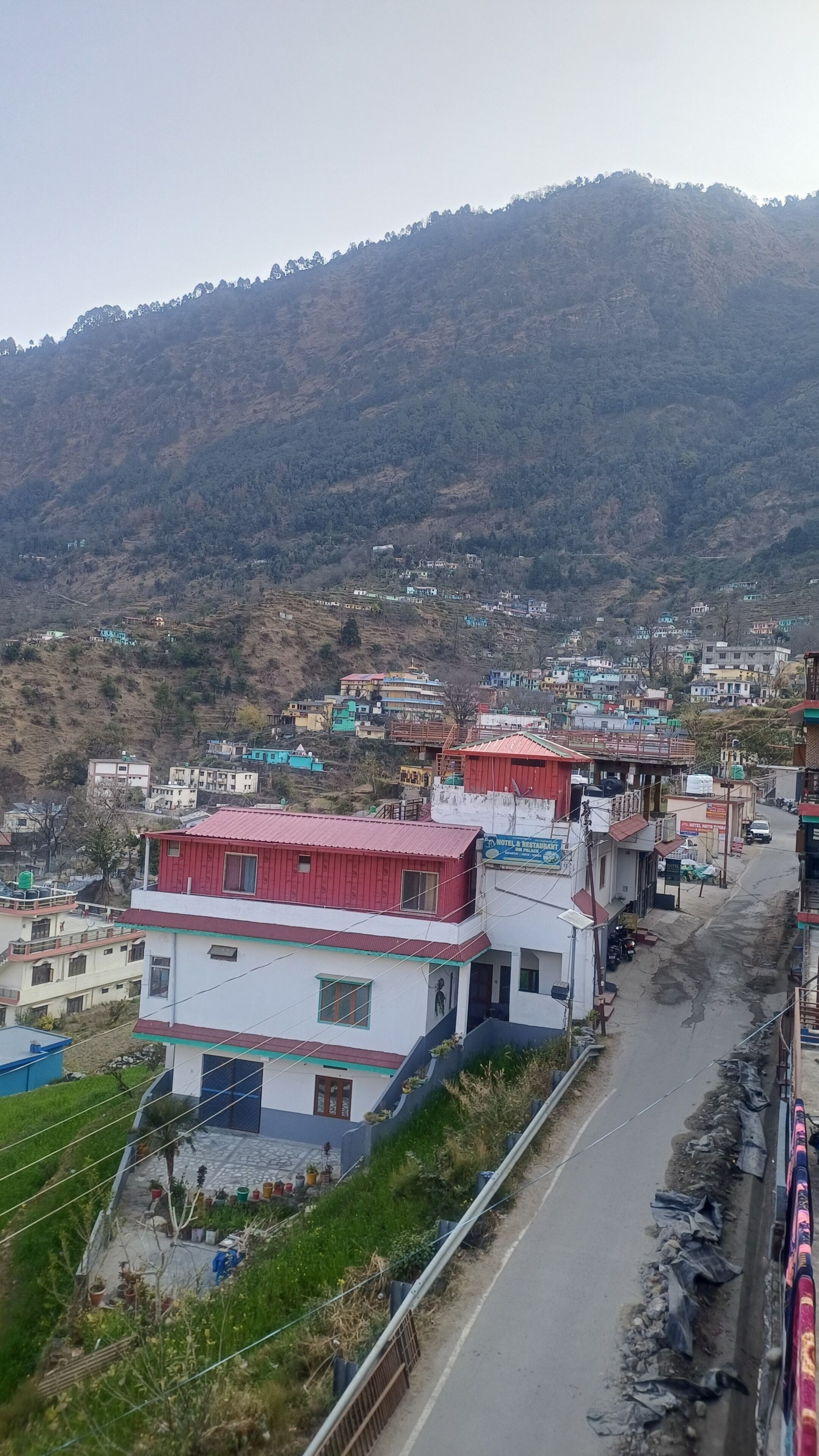 Un pueblo en una colina con edificios, una carretera y un tren.
