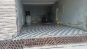 A hallway with a tiled floor, a water tank, and a motorcycle. - Hotel Himalayan View  (Ukhimath)