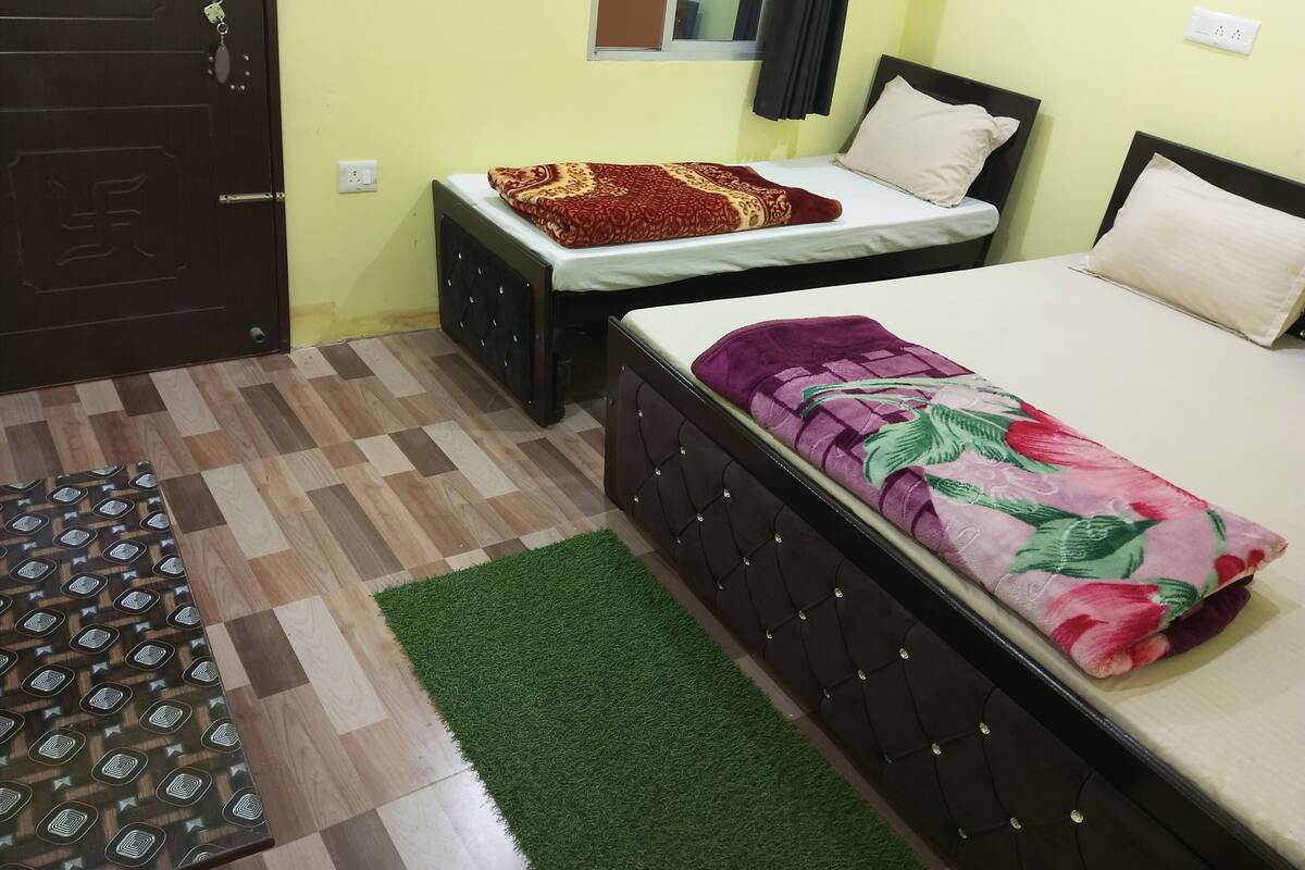 A room with two beds, a patterned rug, and a door.
