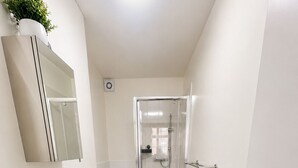 Un baño moderno con lavabo blanco, espejo y cabina de ducha de vidrio.