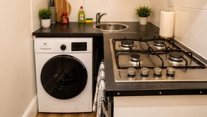 Cocina compacta con lavadora, estufa a gas y pileta.