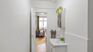 Un pasillo estrecho que conduce a una habitación con un escritorio, una silla y un ventanal.
