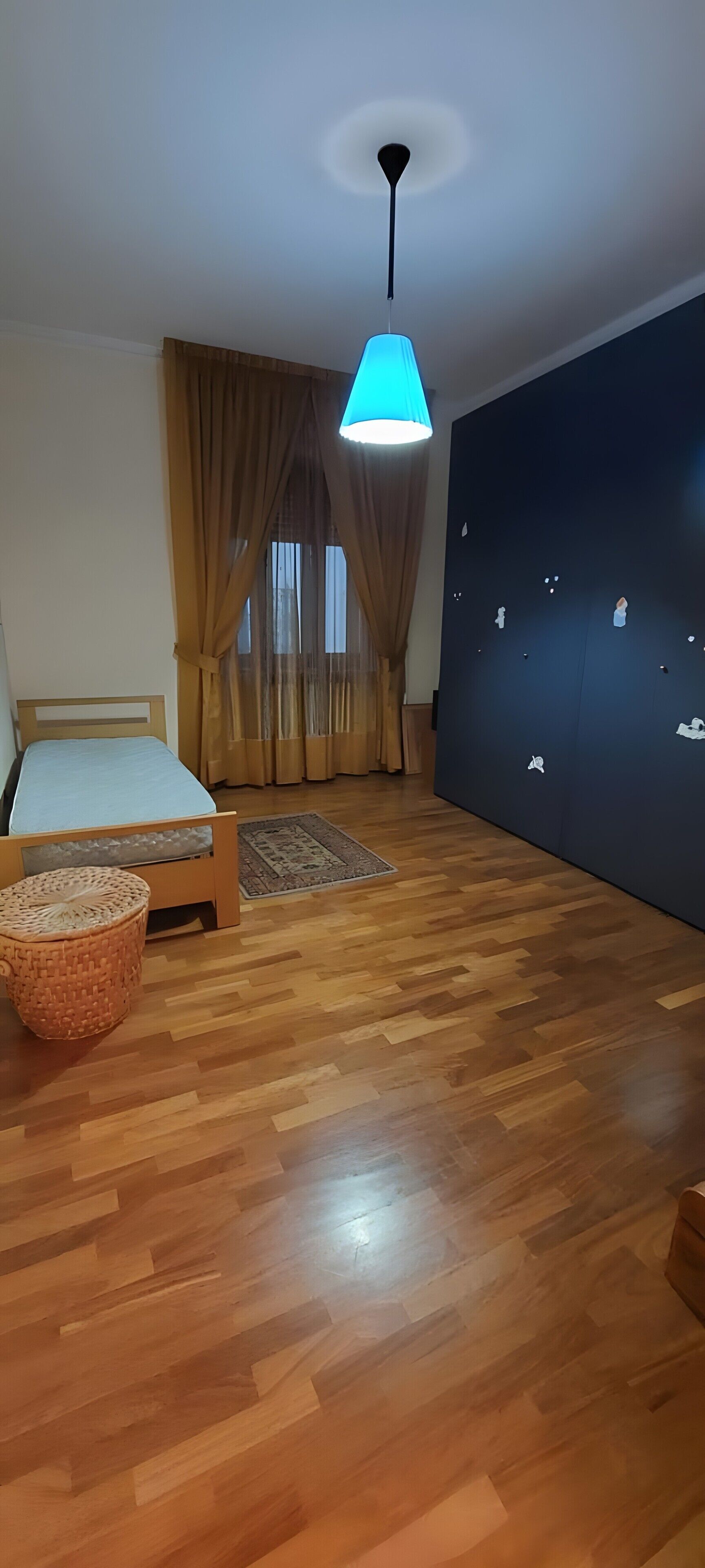 Une pièce comprenant un lit, un luminaire suspendu, un mur agrémenté d’éléments décoratifs et un plancher en bois.