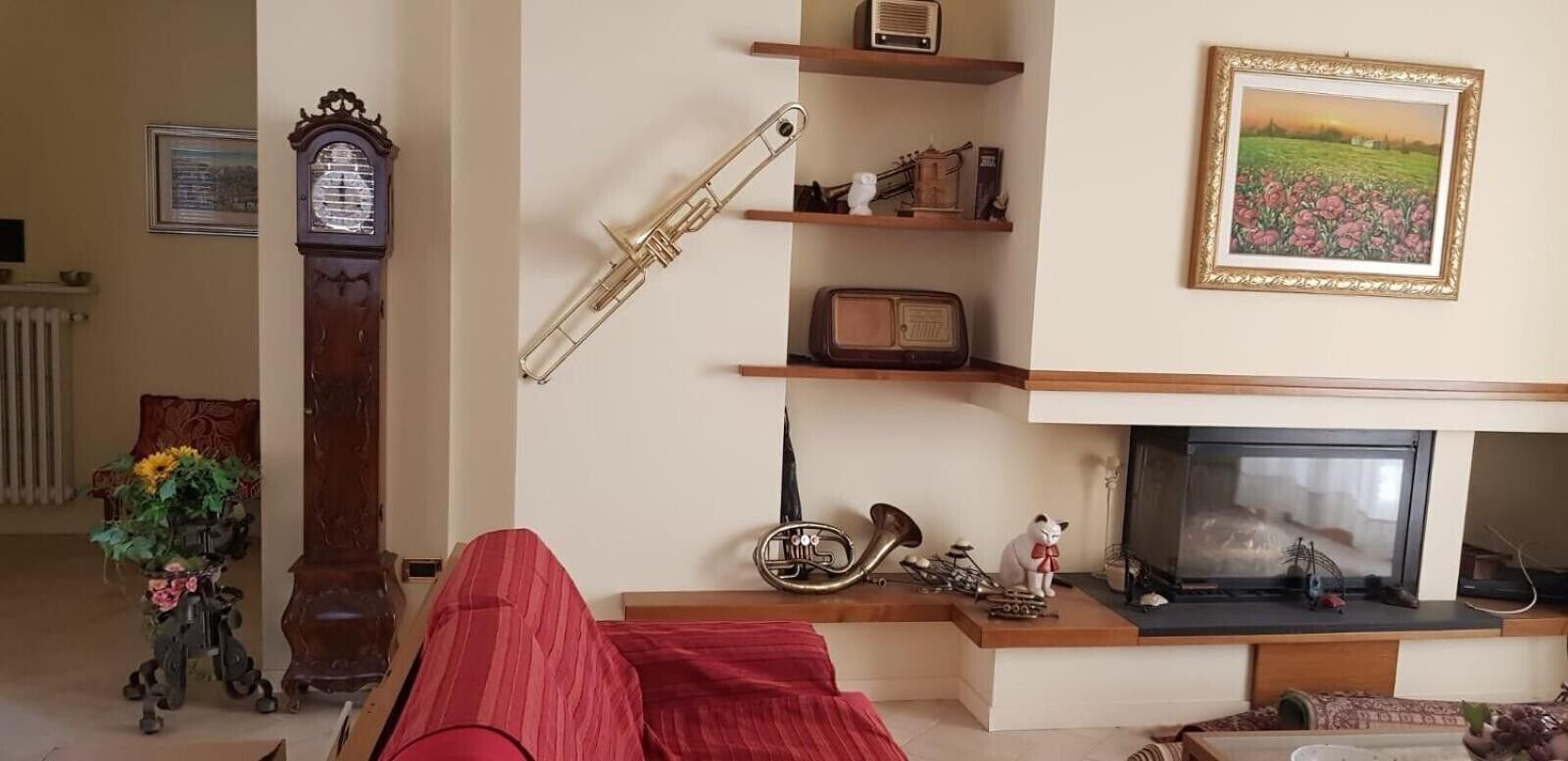 A living room with a fireplace, a clock, a radio, and a framed picture on the wall.