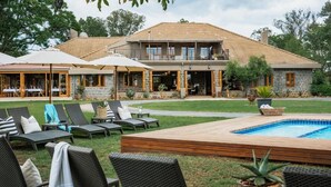 Ein zweistöckiges Haus mit Swimmingpool, Sitzgelegenheiten im Freien und einer überdachten Terrasse.
