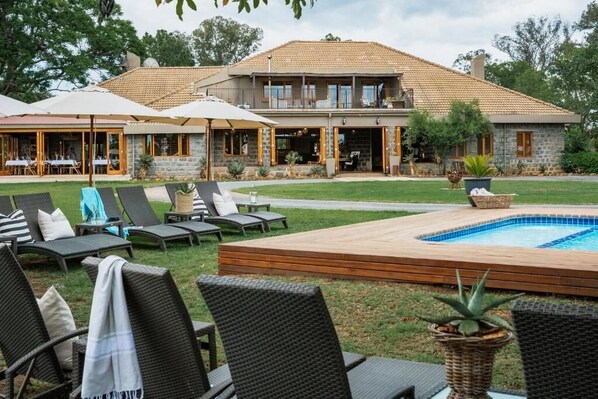A two-story house with a swimming pool, outdoor seating, and a covered patio area.