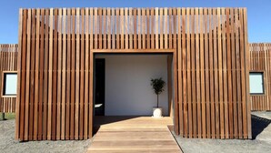 Ein modernes Gebäude mit Holzfassade, einer mittleren Tür und einem kleinen Topfpflanzen.