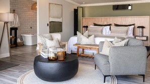 Ein modernes Schlafzimmer mit einem Bett, einem runden schwarzen Couchtisch, einem schwarz-weiß karierten Sessel und einem Holznachttisch.