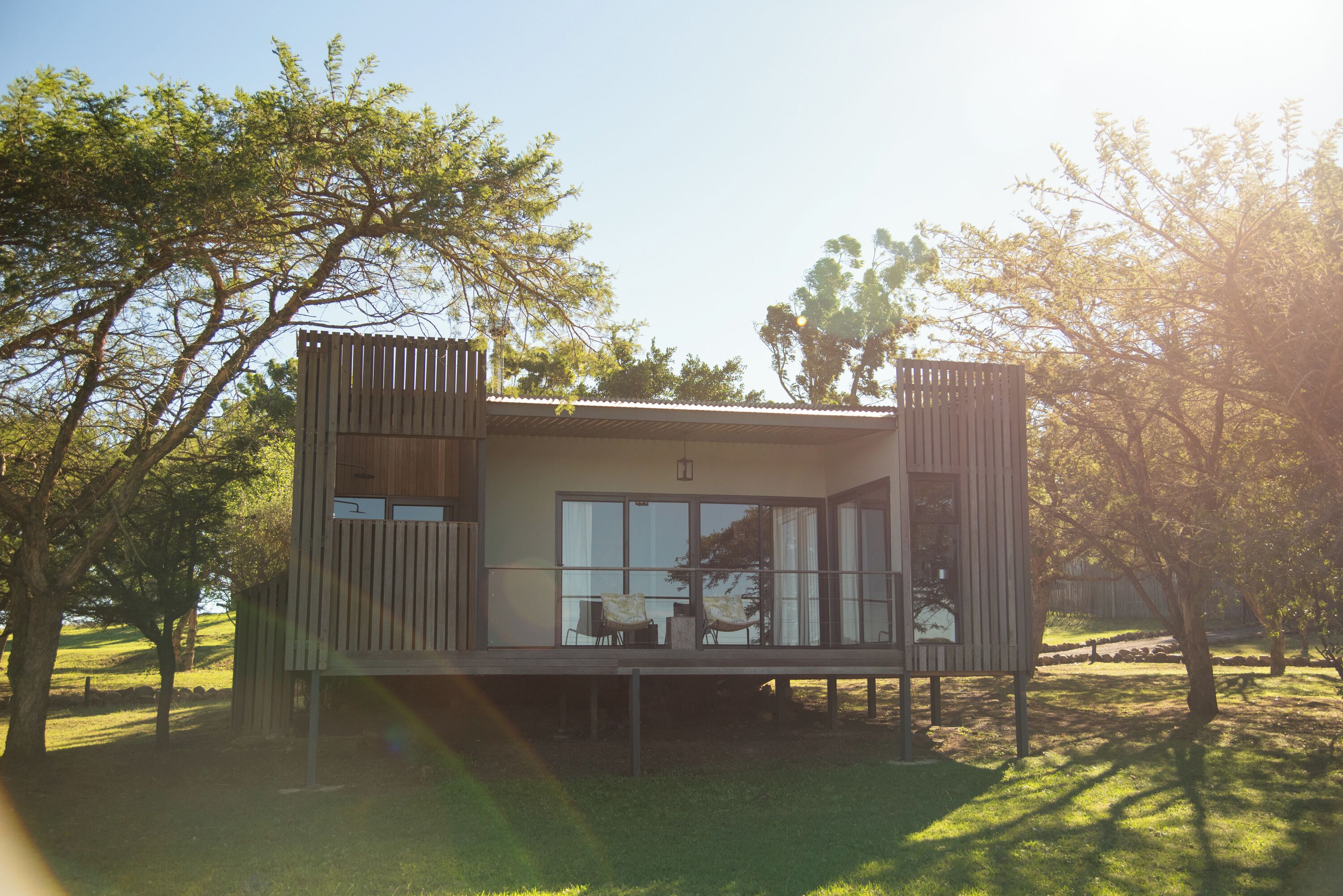 A modern cabin with a balcony, large windows, and a wooden exterior.