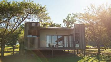 A modern cabin with a balcony, large windows, and a wooden exterior.