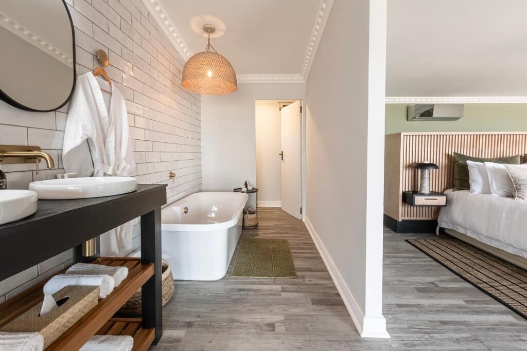 A modern bathroom with a bathtub, a vanity with a mirror, and a hanging light fixture.