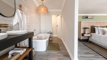 A modern bathroom with a bathtub, a vanity with a mirror, and a hanging light fixture.